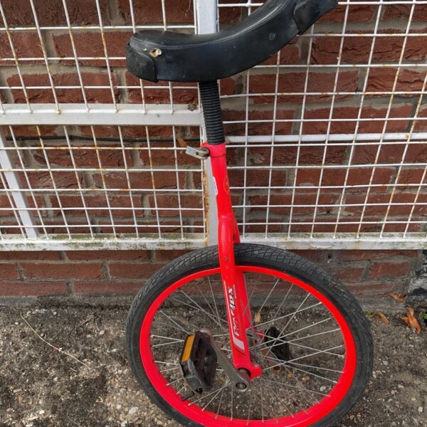 Red Indie trainer unicycle with a worn seat and silver crank.