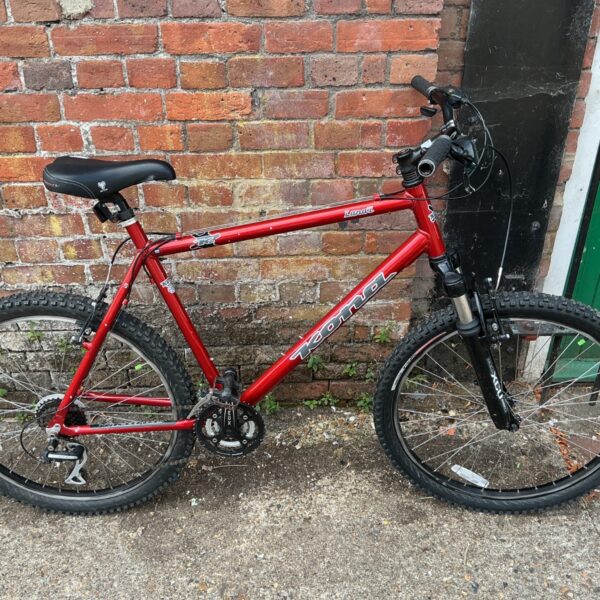 Red Kona mountain bike with front suspension and 26 inch wheels.