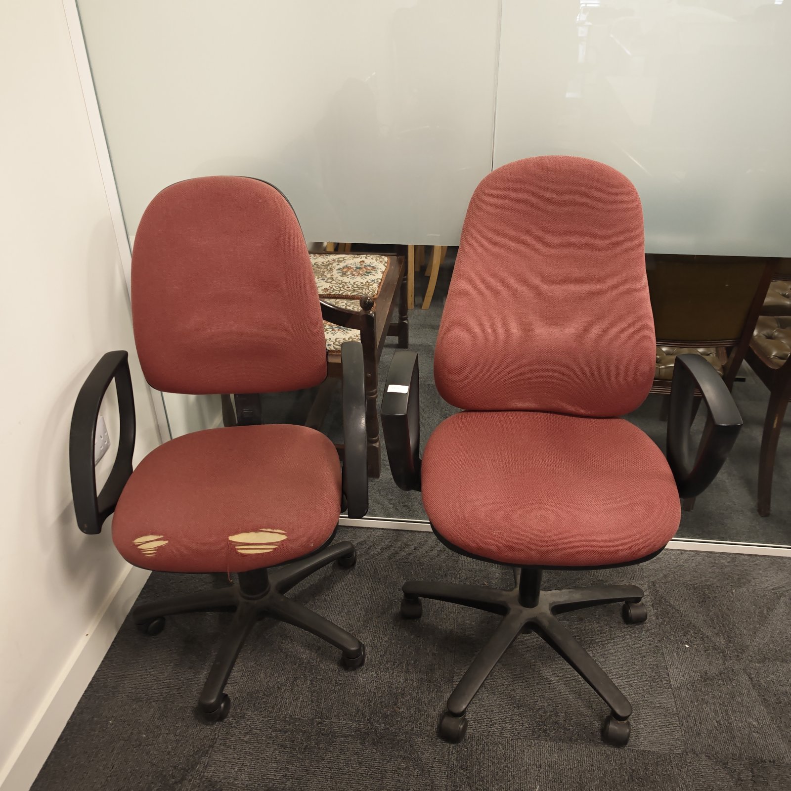 Red office swivel chairs, one needing restoration, vintage style.