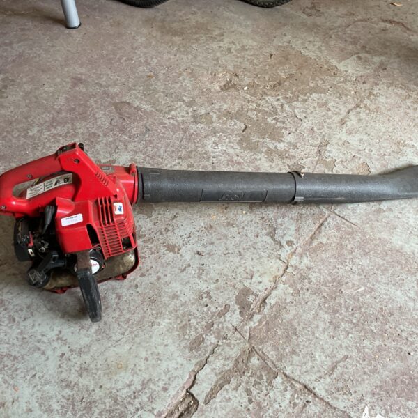 Red handheld petrol leaf blower for garden use.