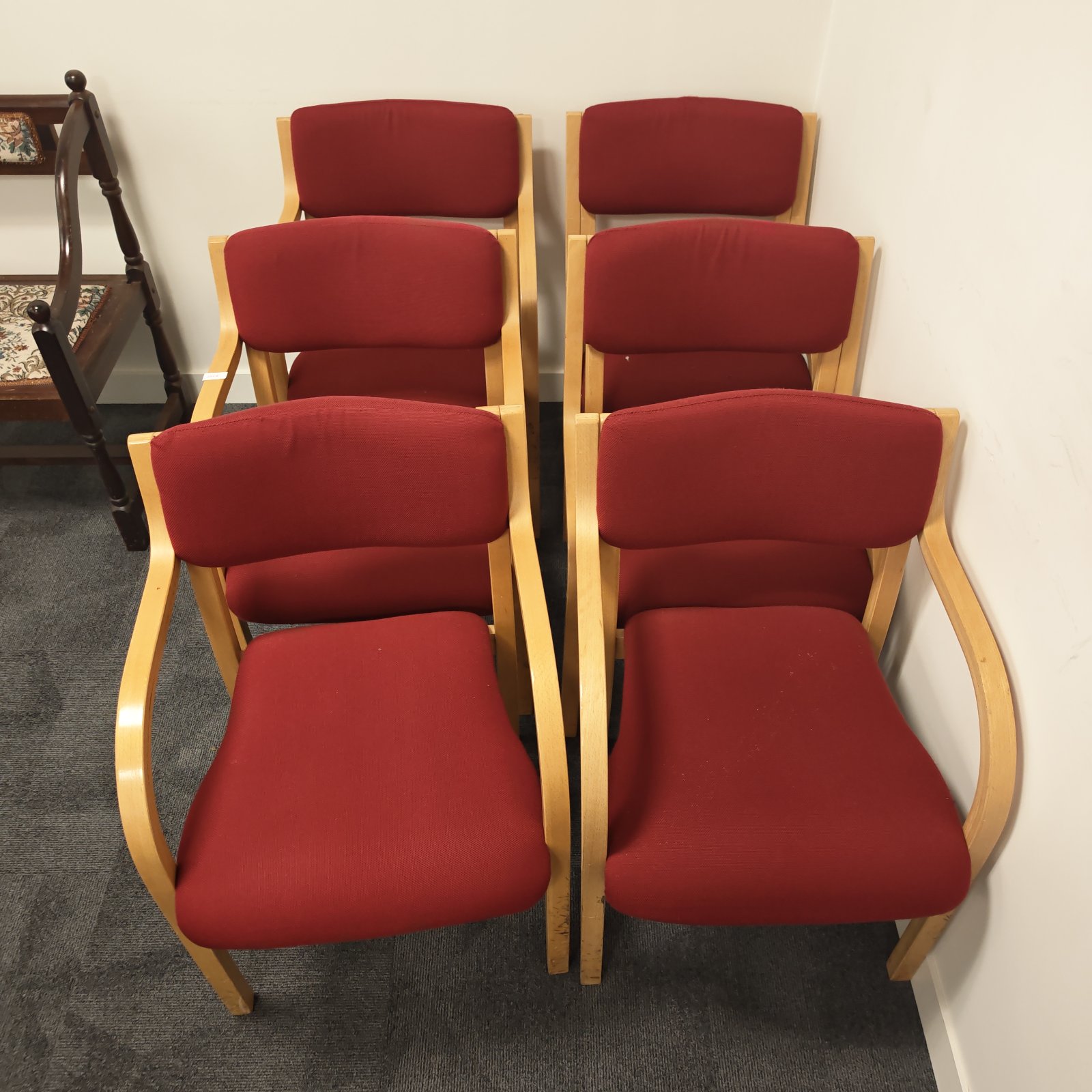 Six red upholstered reception chairs with wooden frames.