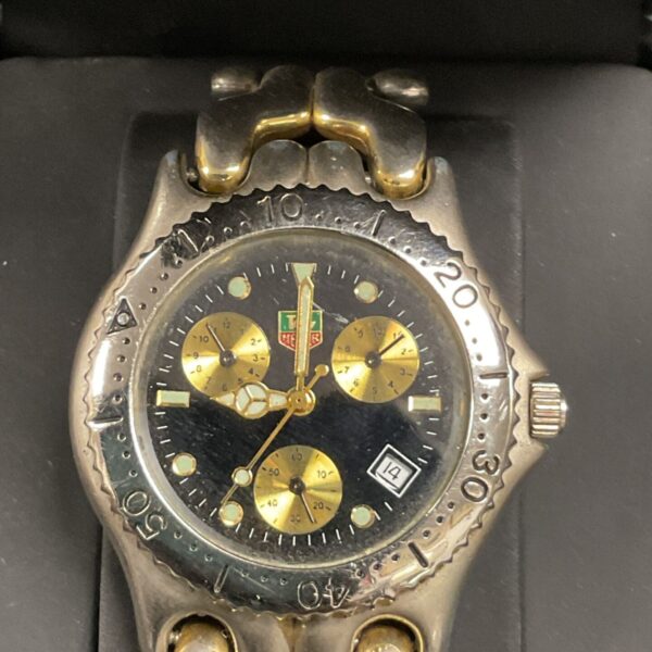 Gold tone replica Tag Heuer quartz wristwatch with black dial.