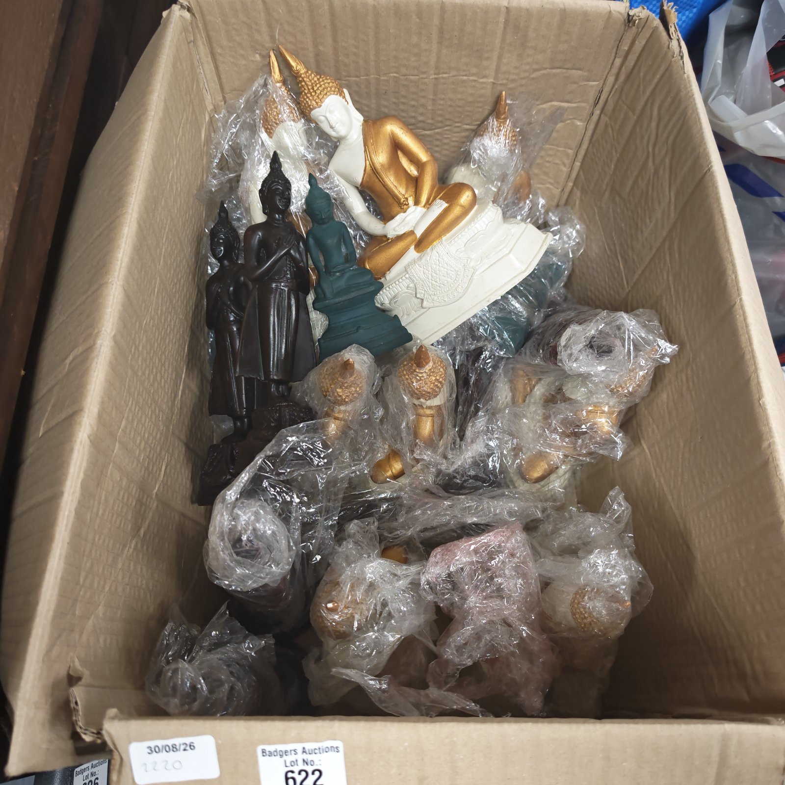 Collection of resin Buddhist statues in a cardboard box.