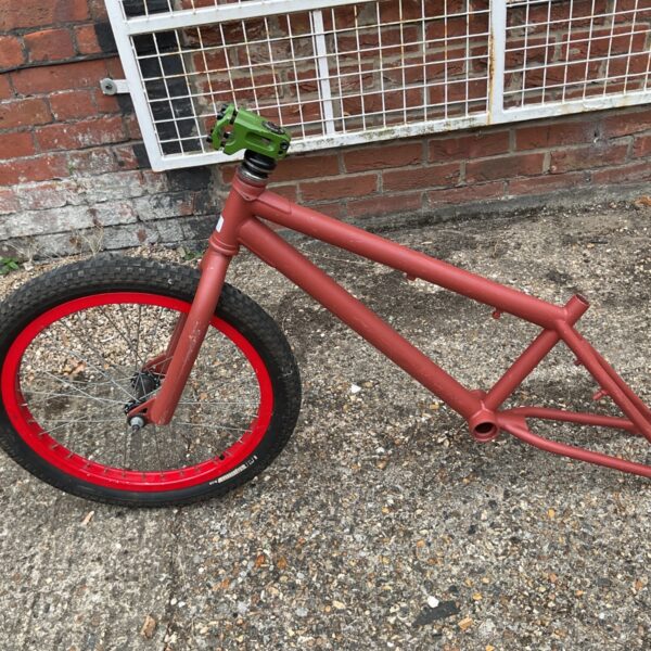 Retro Haro BMX frame with red wheel and primed finish.