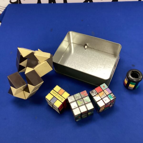 Rubik's Cube lot with various puzzles inside a metal tin.