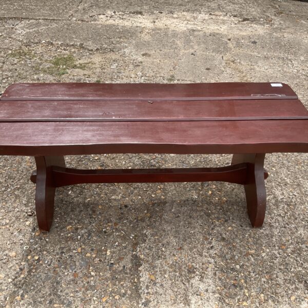 Rustic brown wooden garden bench in a garden setting.