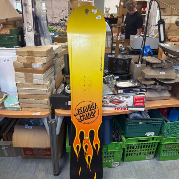Santa Cruz FW164 snowboard with flame graphics in a cluttered space.