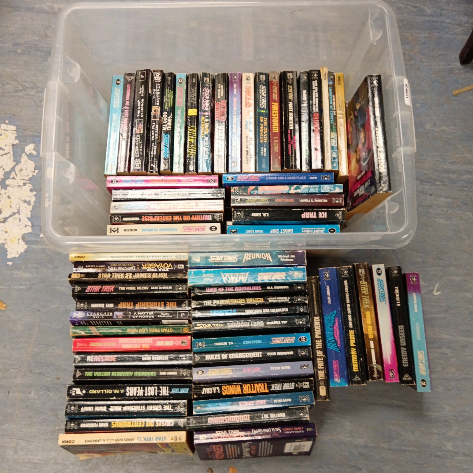 Stack of vintage sci-fi books including Star Trek and Stargate novels.