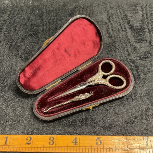 Antique silver button hook and scissors set in open case.