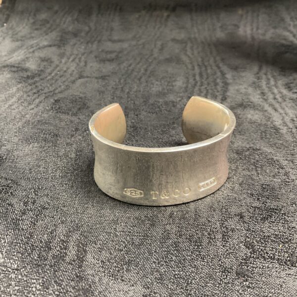 Close-up of a vintage silver cuff bracelet with textured band.