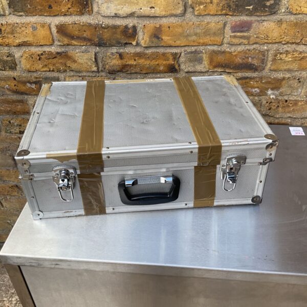 Damaged silver flight case with locking clasps and handle.