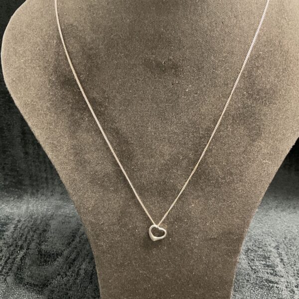 Delicate silver heart necklace on a neutral background.