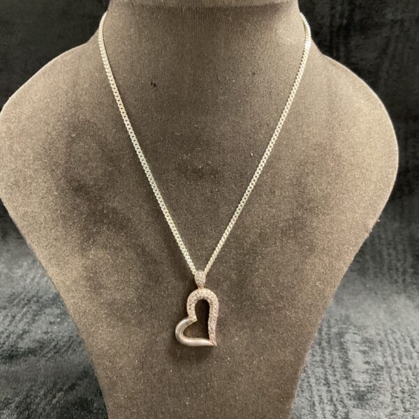 Silver heart pendant necklace with stone detailing on a chain.