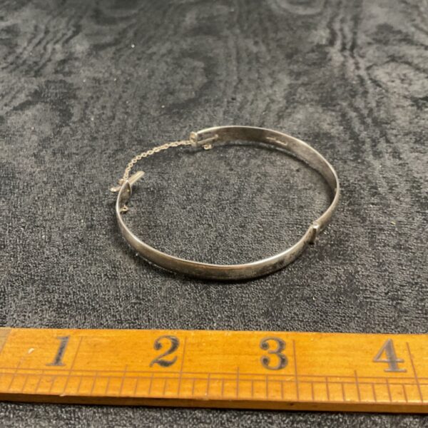 Silver hinged bracelet with ruler for scale.