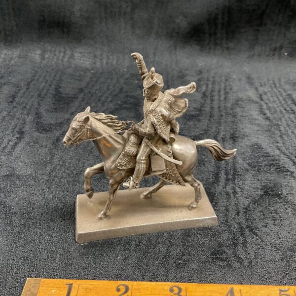 Antique silver Napoleonic cavalry officer figurine on a ruler.