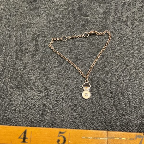 Delicate silver bracelet with a snowman pendant for winter wear.