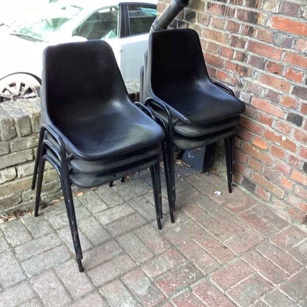 Six vintage plastic stacking chairs in a garden setting.