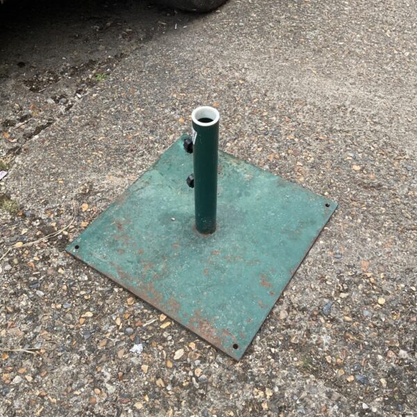 Green square metal parasol base with signs of weathering.