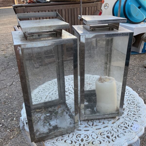 Pair of contemporary stainless steel candle lanterns for modern home decor.