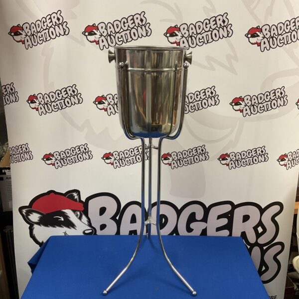 Stainless steel champagne ice bucket on tripod stand for serving drinks.