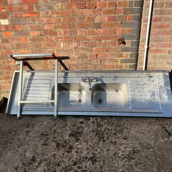 Stainless steel double bowl kitchen sink with chrome tap and frame.