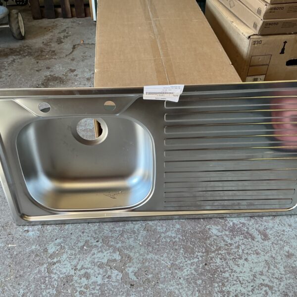 Stainless steel kitchen sink with a single bowl, showing signs of wear.
