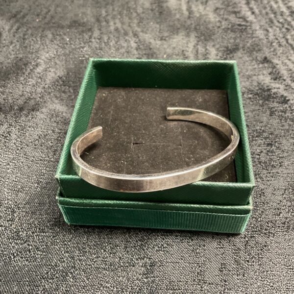 Elegant sterling silver bracelet displayed on a green box.