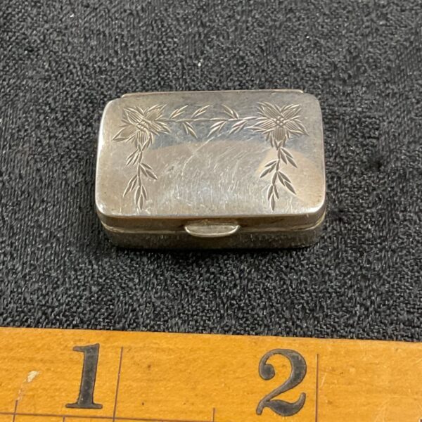 Antique sterling silver pill box with floral engraving.