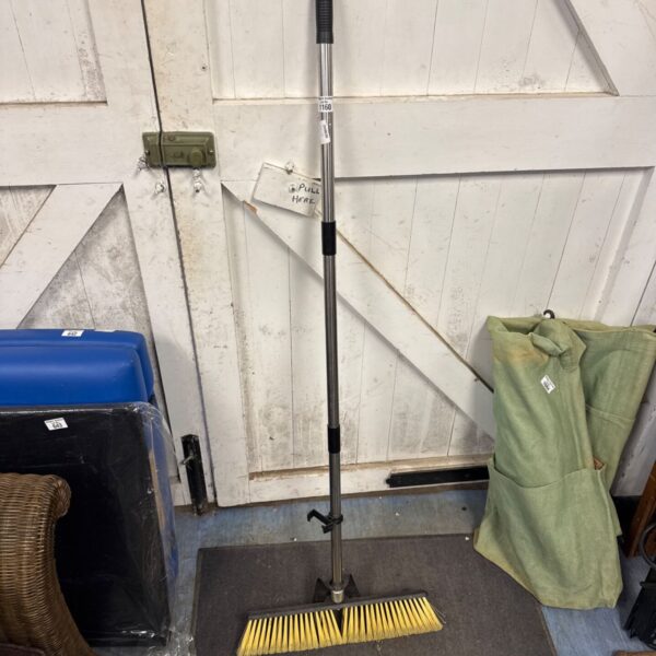 Metal handled stiff broom for household cleaning.