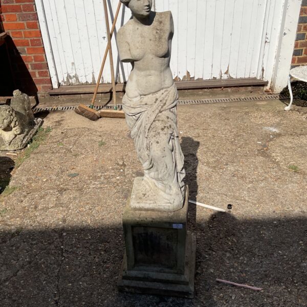Weathered stone garden Venus statue on a plinth.
