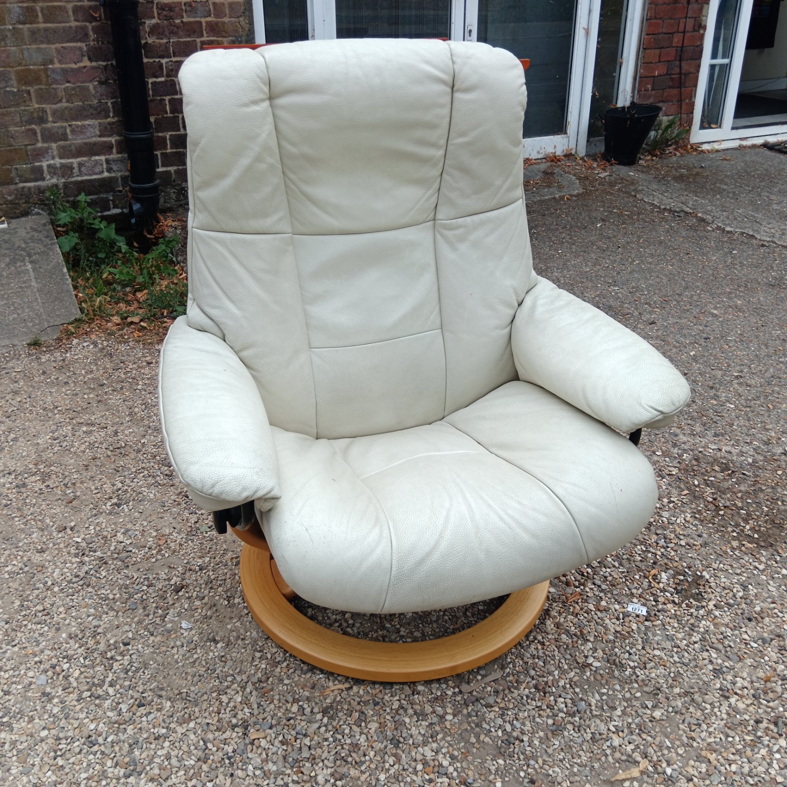 Cream leather Stressless reclining armchair with wooden base.
