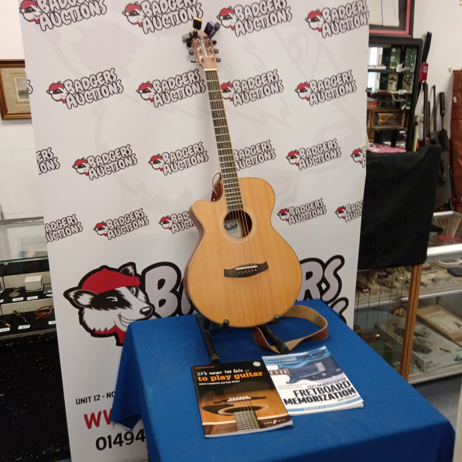 Tanglewood acoustic guitar with books and accessories displayed on a stand.