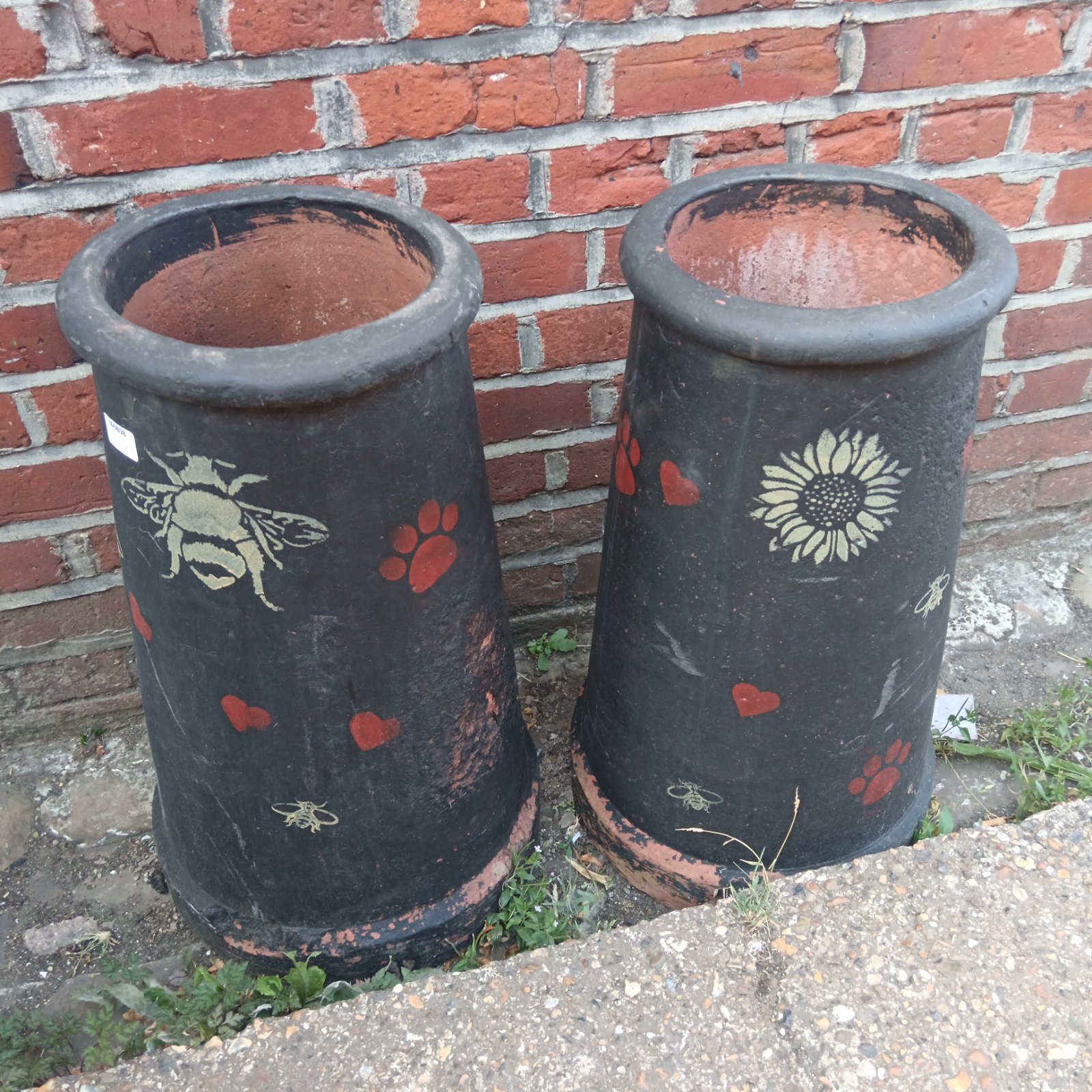 Pair of large terracotta chimney pots with bee and floral design.