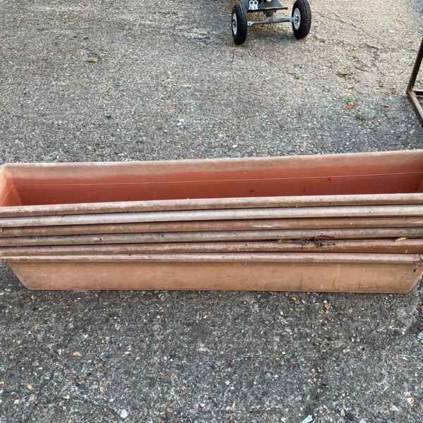 Set of six rustic terracotta garden troughs for plants.