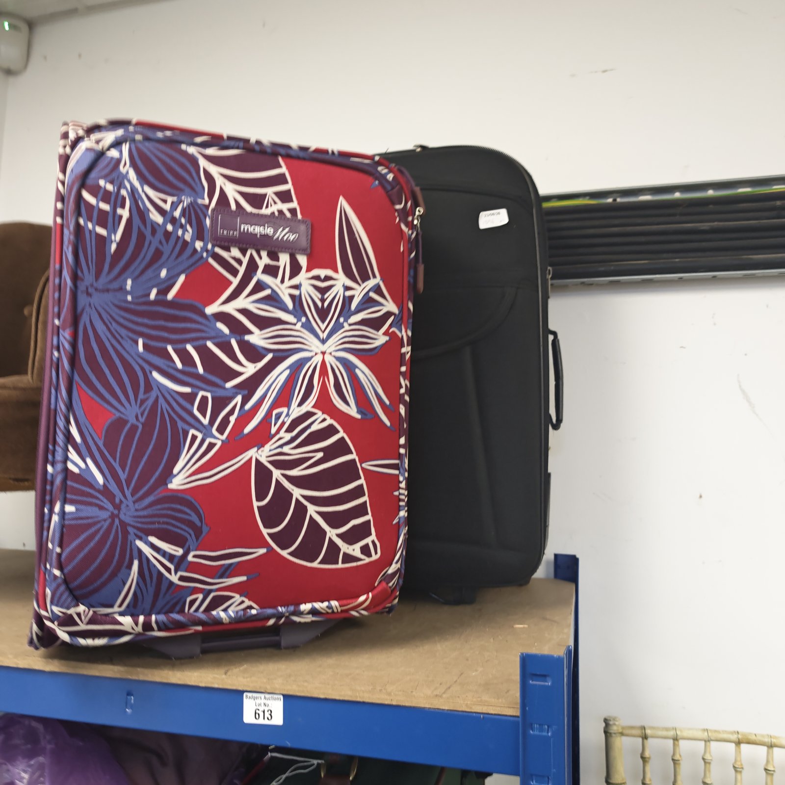 Red floral patterned Tripp suitcase with wheels and extending handle.