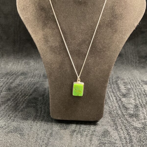 Bright green turquoise pendant on a silver chain necklace.