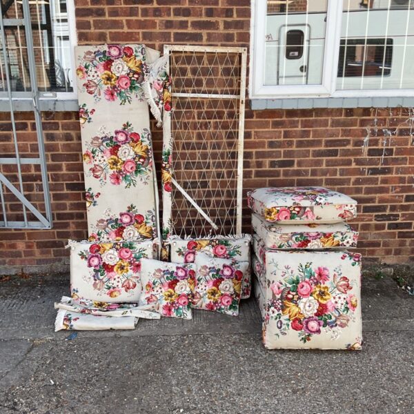 Victorian floral cushions and panels displayed against a brick wall.