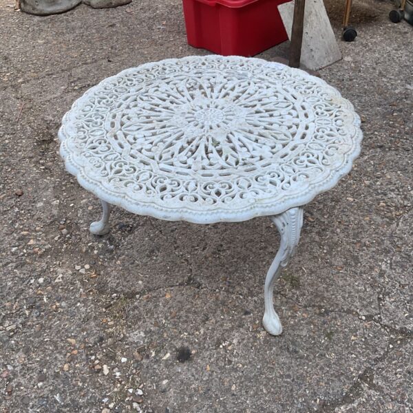 White Victorian garden table with floral lattice design.