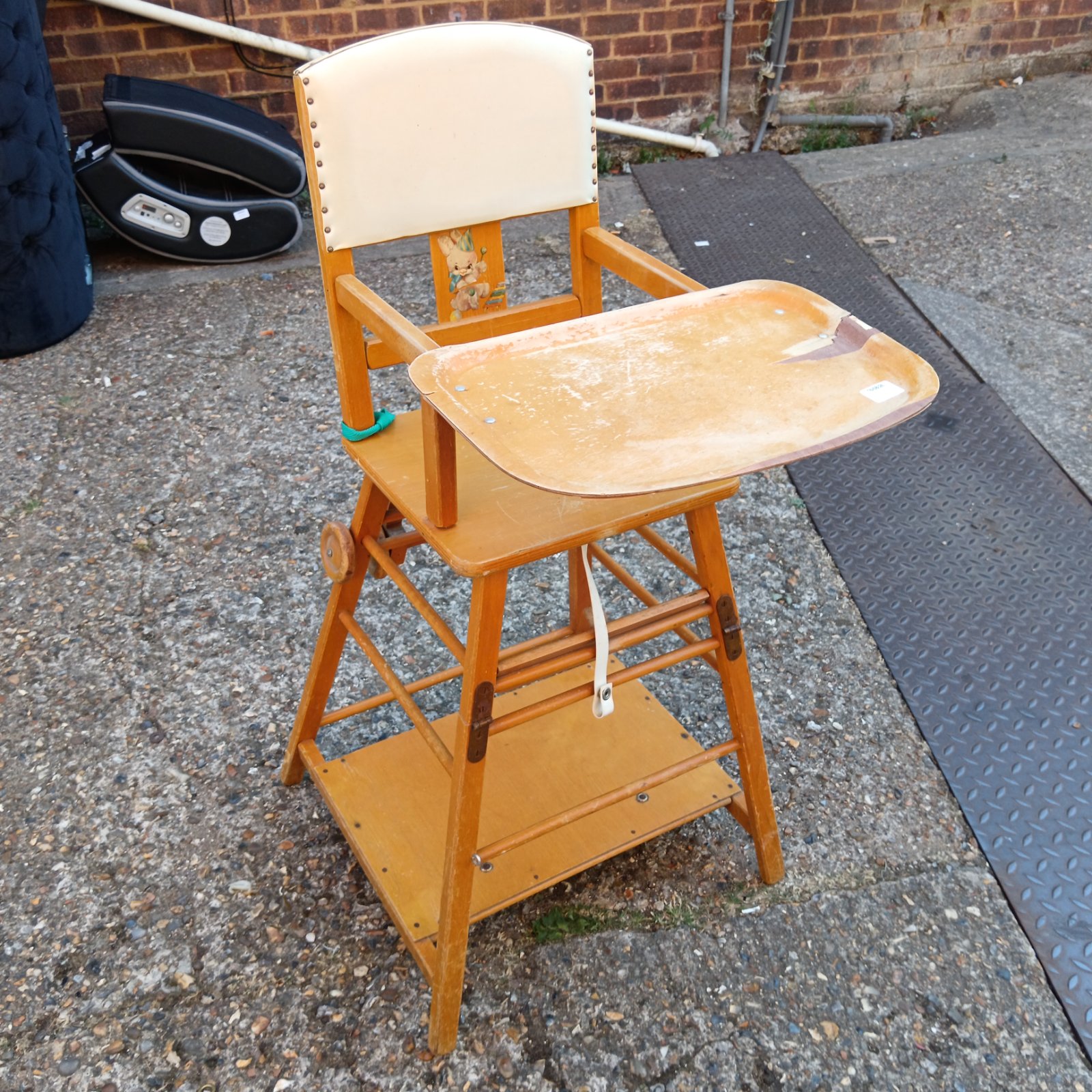 Vintage 1950s wooden baby high chair with a faded tray.