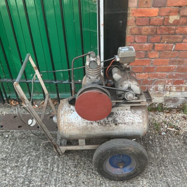 Vintage air compressor on wheels with red guard.