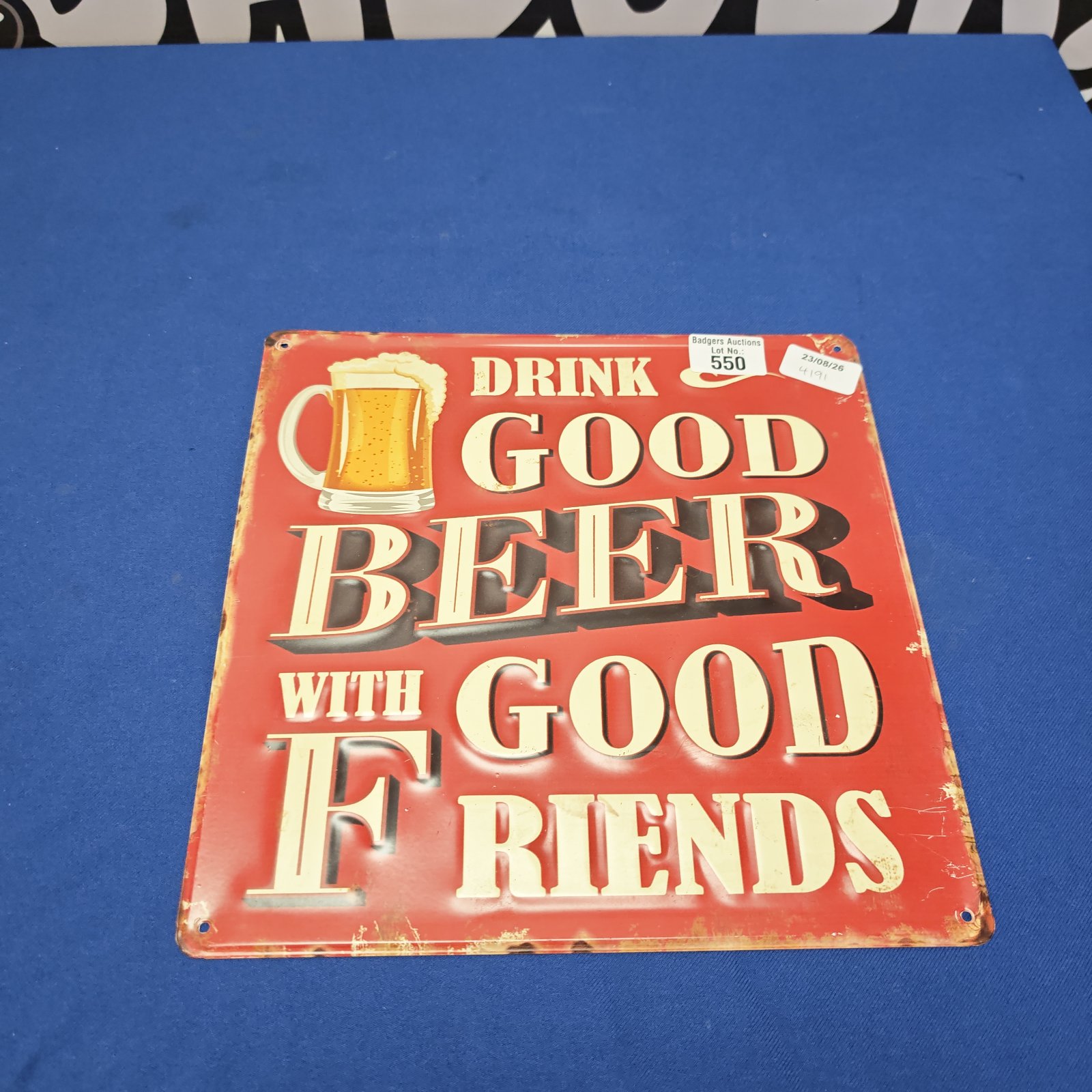 Vintage tin wall sign reading "Drink good beer with good friends".