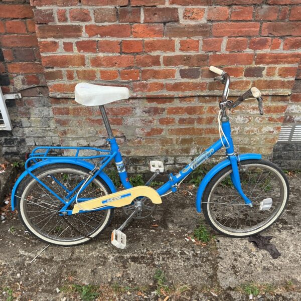 Vintage blue folding bicycle with white saddle and chain guard.