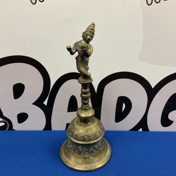 Vintage brass pooja bell with engraved dome and figurine handle.