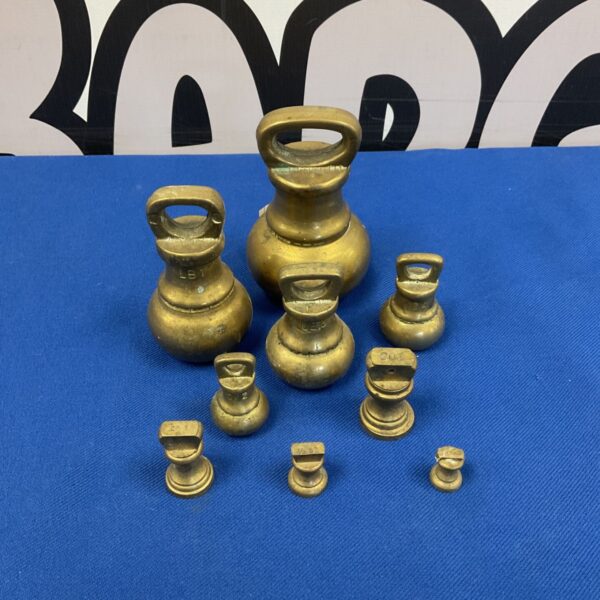 Vintage brass scale weights set on a dark background.