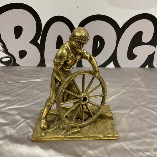 Vintage brass wheelwright sculpture with a large wheel.