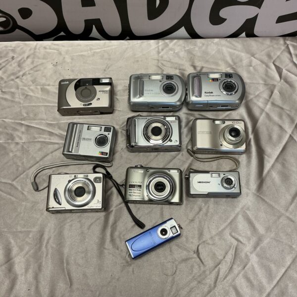 Assorted vintage digital cameras including Kodak, Sony, Nikon, and Fujifilm.