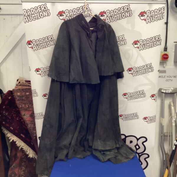 Dramatic black vintage cape displayed against a backdrop.