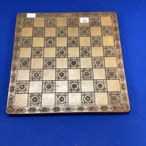 Vintage carved wooden chessboard with detailed floral designs.