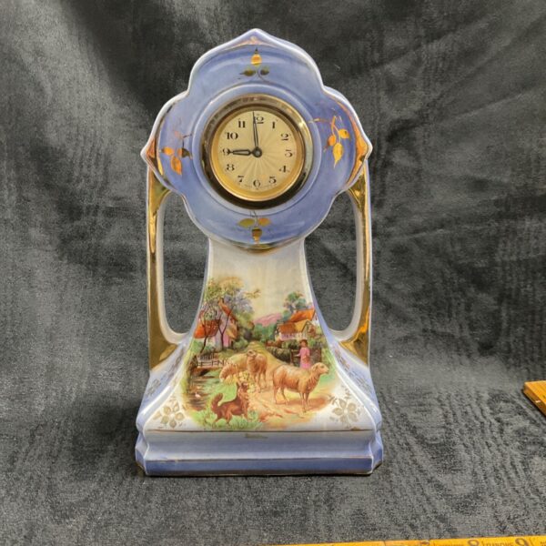 Vintage ceramic mantle clock with pastoral scene.