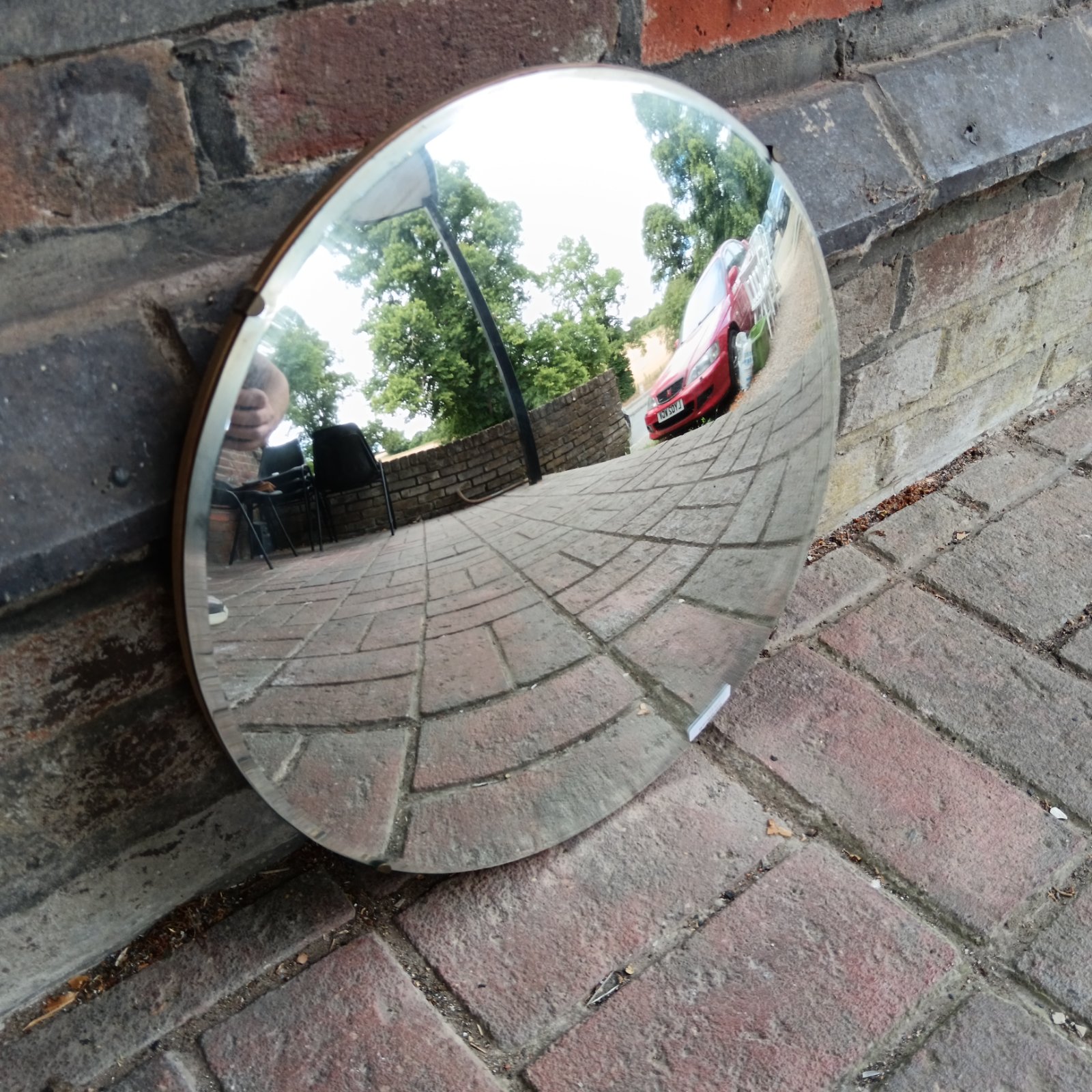 Vintage round convex wall mirror reflecting a garden scene.